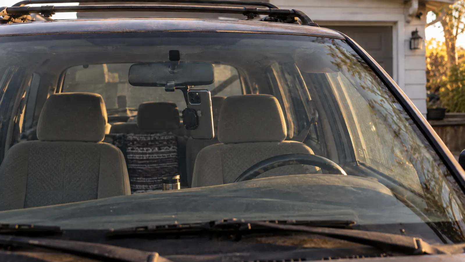 A magnetic phone mount attached to the windshield of an older SUV, with the phone facing the driver